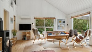 A spacious living room with a large TV, wooden flooring, and a cozy seating area with a sofa and chairs. - Awesome home in Aakirkeby with WiFi (Aakirkeby)