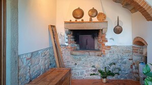 A rustic stone fireplace with a wooden mantel, surrounded by stone walls and a tiled floor. - Stunning apartment in Rignano sull'Arno (Rignano sull'Arno)
