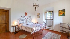 A bedroom with a metal bed frame, a wooden door, a window with a view, a radiator, and a painting on the wall. - Stunning apartment in Rignano sull'Arno (Rignano sull'Arno)