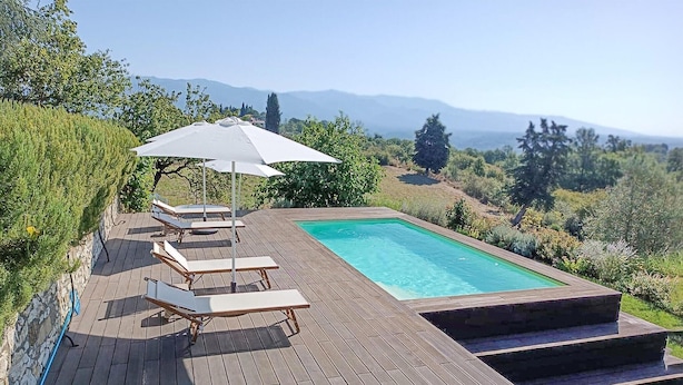 A wooden deck with a swimming pool, lounge chairs, and an umbrella. - Stunning apartment in Rignano sull'Arno (Rignano sull'Arno)