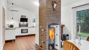 Eine moderne Küche mit Kamin aus Backstein, weißen Schränken und einem großen Fenster.
