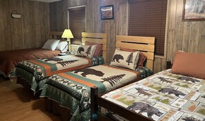 A room with two beds, each with a unique animal-themed quilt, wooden headboards, and a lamp on the nightstand.
