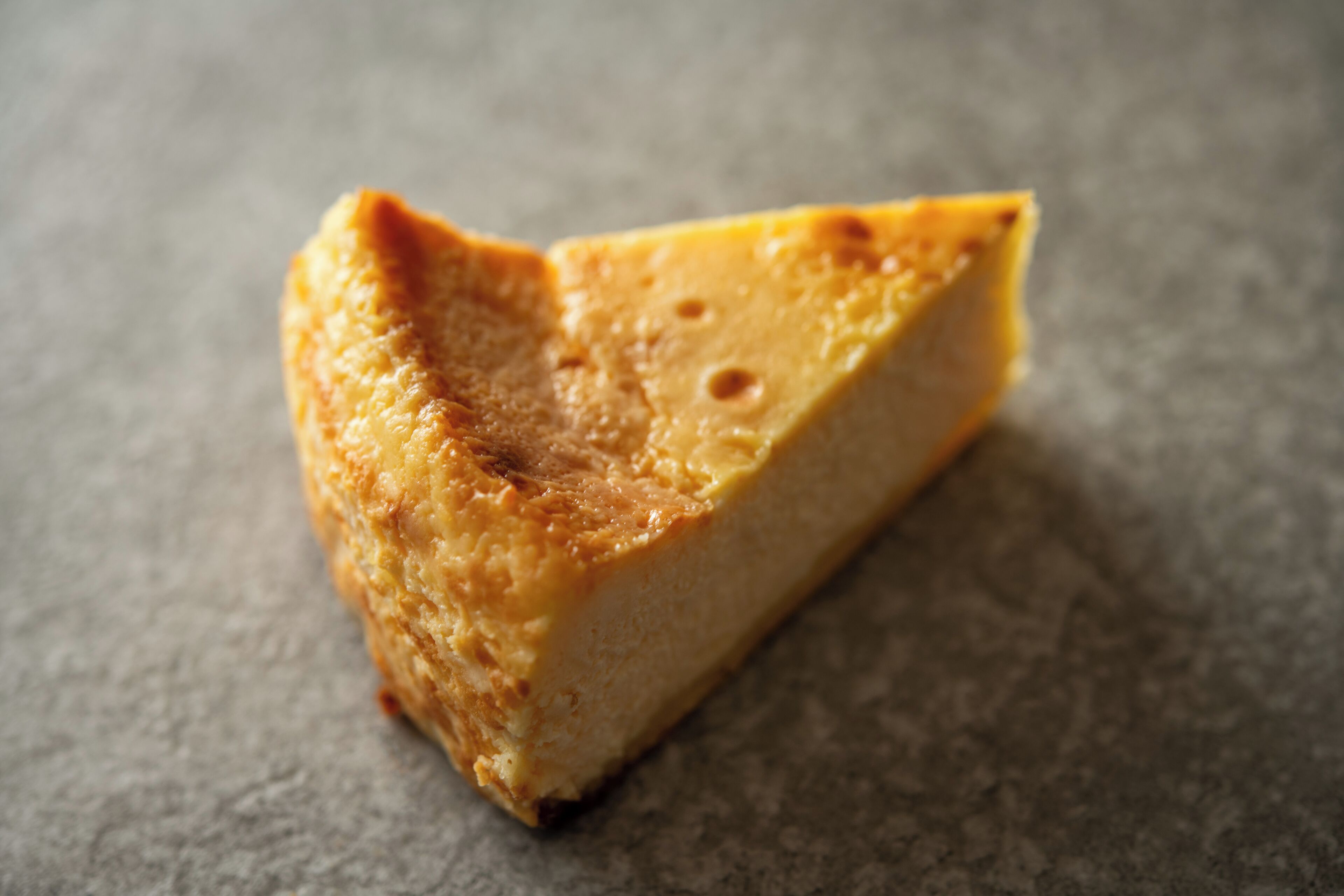A slice of cheesecake on a textured surface.