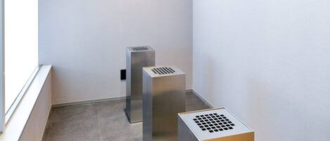 A narrow hallway with a window on the left and two metallic vents on the floor.