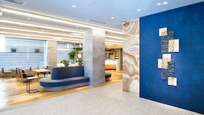 Un hall d’entrée moderne avec un mur d’accent bleu, des espaces de détente et un comptoir d’accueil.