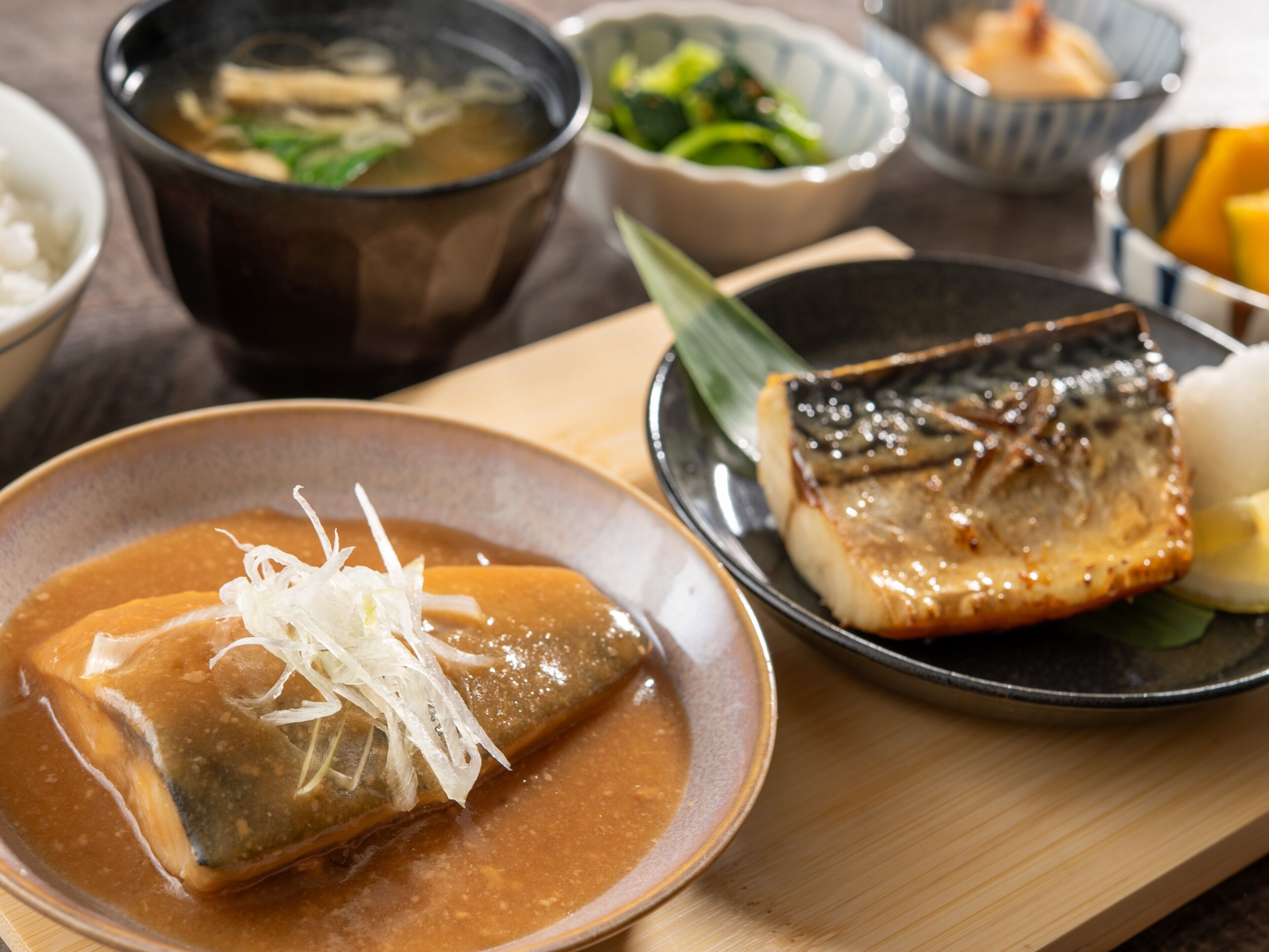 Variedad de platos japoneses, incluyendo un tazón de sopa, un plato con pescado a la parrilla y un bol de tofu.