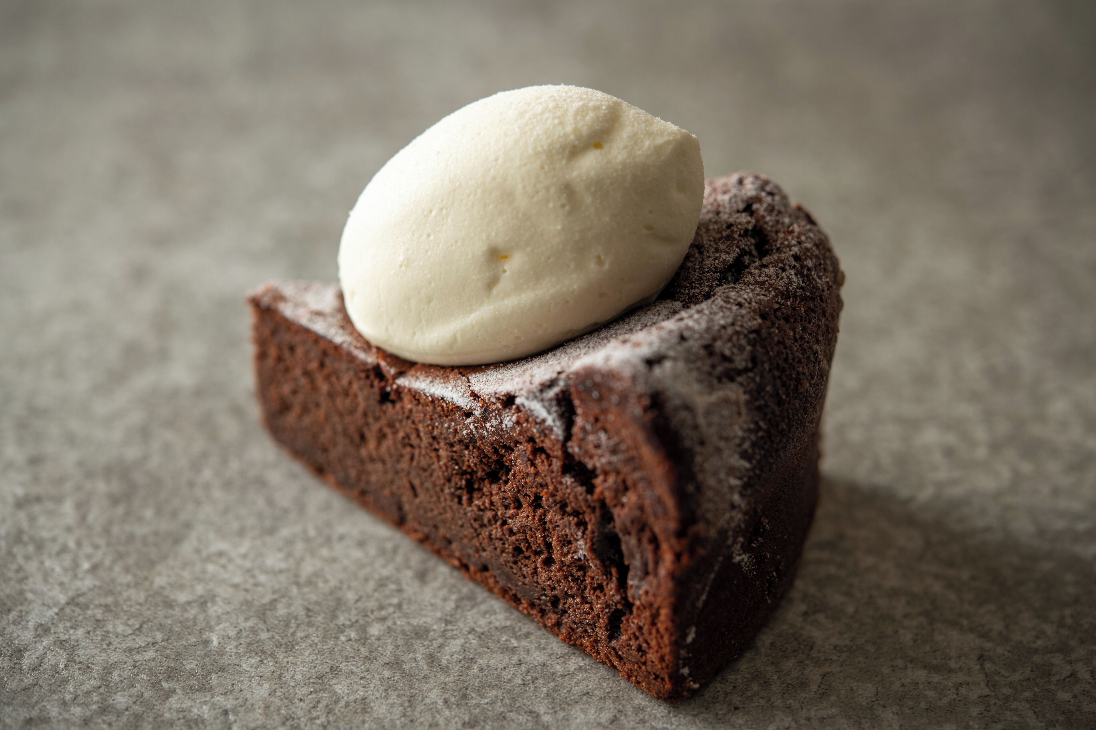 A slice of chocolate cake with a scoop of vanilla ice cream on top.