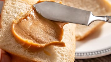 Un cuchillo untando mantequilla de maní sobre una rebanada de pan.