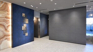 Un couloir moderne avec un mur en marbre, un mur d’accent bleu agrémenté de panneaux décoratifs et un grand panneau gris.