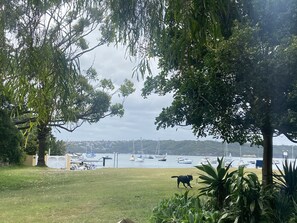 Guests can enjoy a serene grassy area surrounded by lush greenery and a marina with docked boats.