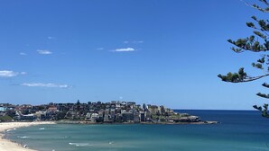 Une ville côtière avec une plage, un ciel bleu dégagé et des bâtiments qui bordent le littoral.