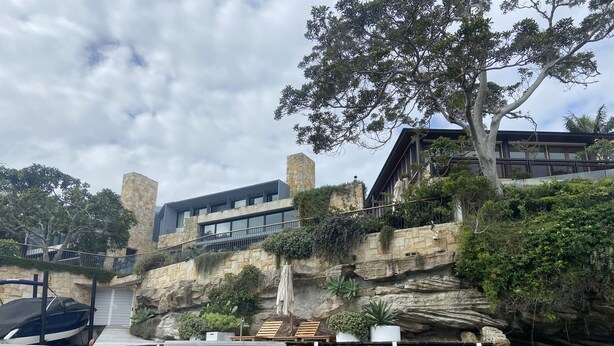 Un bâtiment moderne avec une façade en pierre, une jetée en bois et une falaise rocheuse.