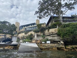 Situated on a rocky outcrop, this structure offers a natural view of the surrounding area and access to a boat via a dock.