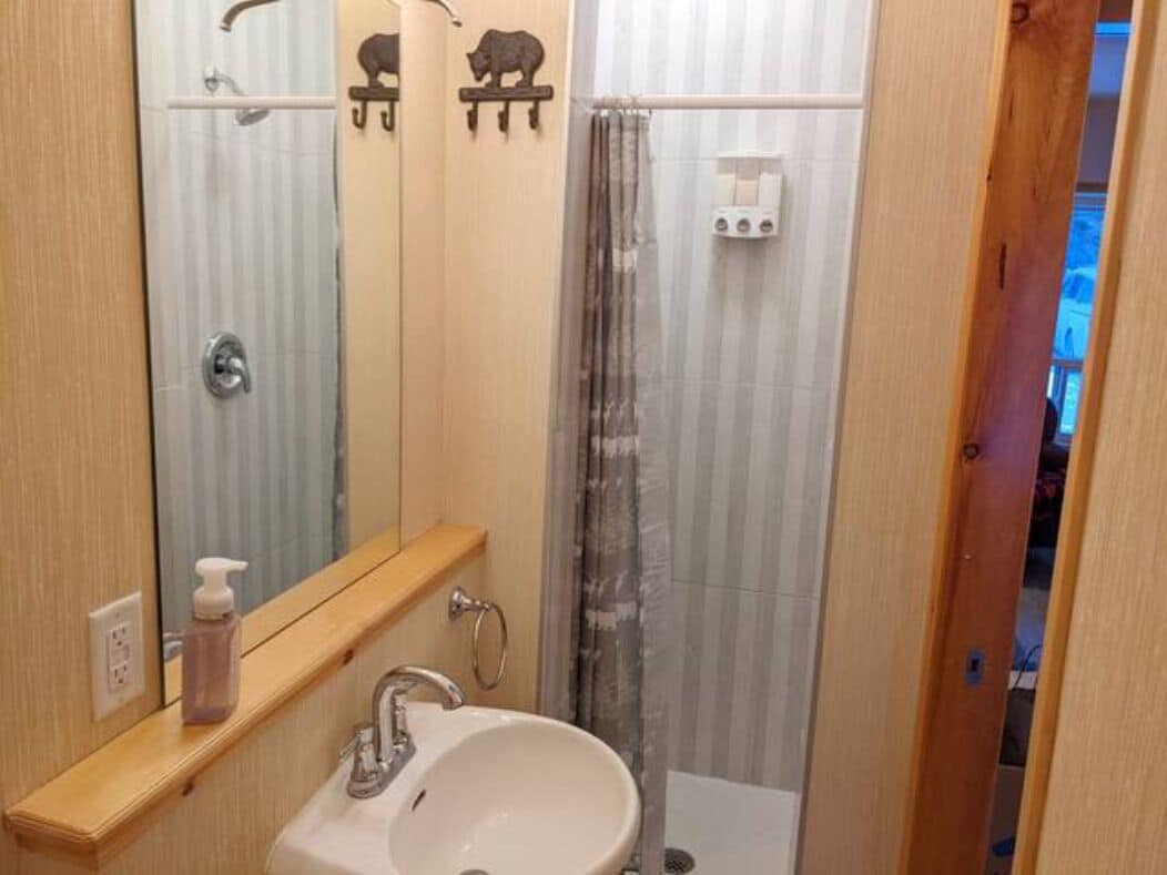 Un baño con lavamanos, espejo y ducha.