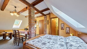 A bedroom with a wooden bed, a dining table, and chairs. There is a skylight above the bed and a brick pillar in the center. - Chlívce u Hronova by Interhome (Chlivce)
