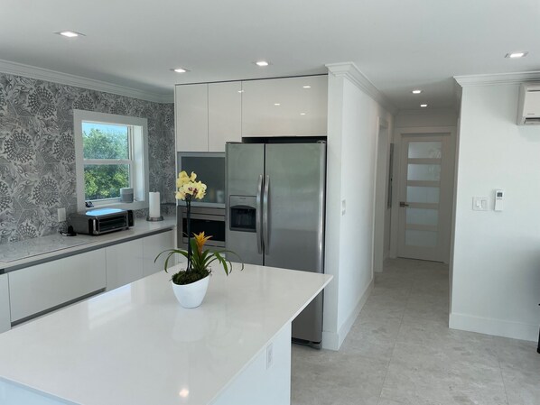 A modern kitchen with a central island, stainless steel appliances, and a patterned backsplash.