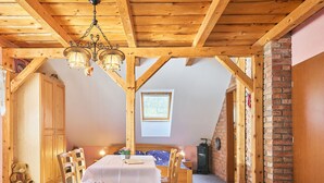 A cozy room with a wooden table, chairs, a teddy bear, and a fireplace.