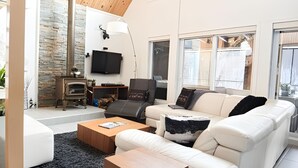 Un salon moderne avec un canapé blanc, une table basse en bois et une cheminée en pierre.