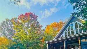 Une maison à deux étages avec un balcon et un véhicule rouge garé devant.