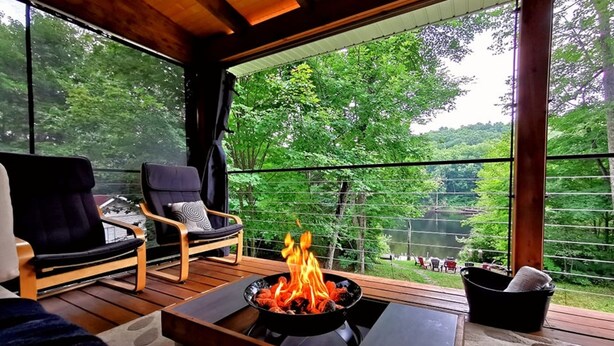 Un espace extérieur accueillant, aménagé avec deux chaises, un foyer et offrant une vue sur un paysage verdoyant et luxuriant.