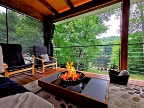 Un espace extérieur accueillant, aménagé avec deux chaises, un foyer et offrant une vue sur un paysage verdoyant et luxuriant.