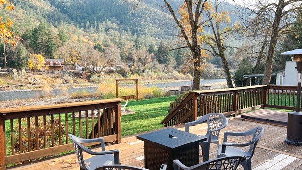 Een terras met buitenmeubilair met uitzicht op een rivier en beboste heuvels.