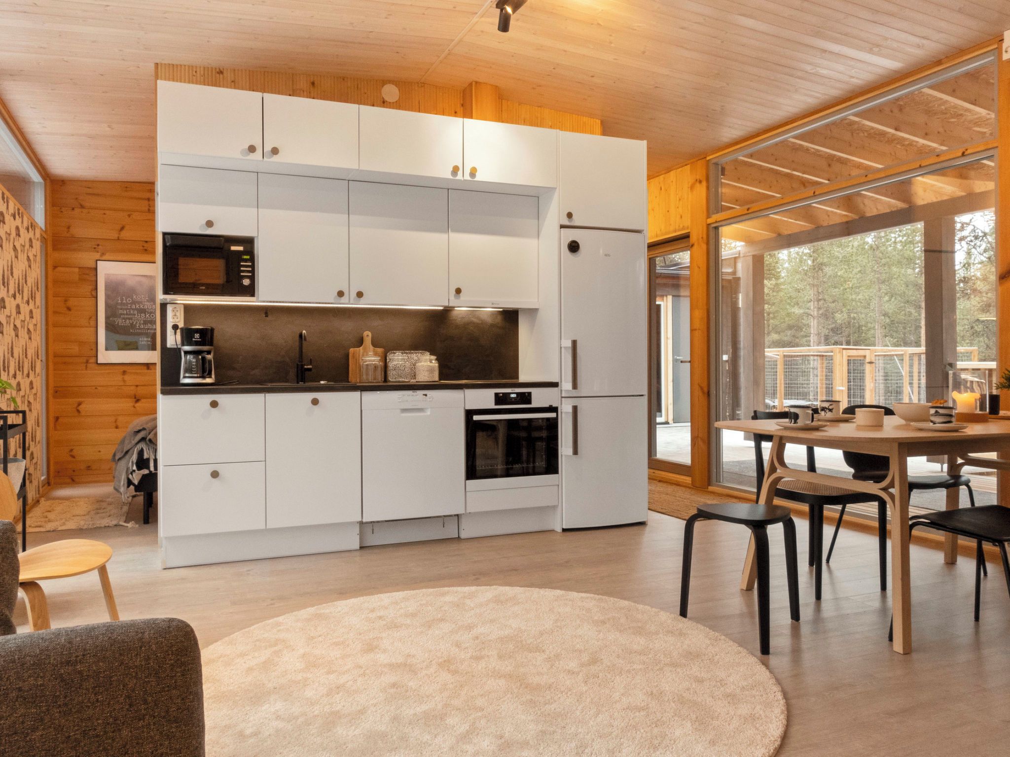 Una cocina moderna con armarios blancos, horno integrado y comedor con mesa y sillas de madera.