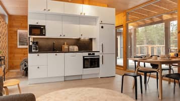 A modern kitchen with white cabinets, a built-in oven, and a dining area with a wooden table and chairs.