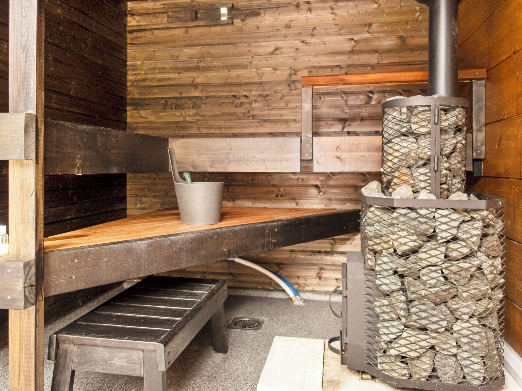 Un intérieur rustique en bois, avec un poêle à bois encastré, un banc et une petite table.