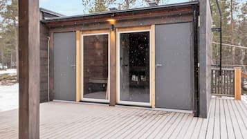 A wooden deck with a modern building featuring large glass doors and a metal railing.