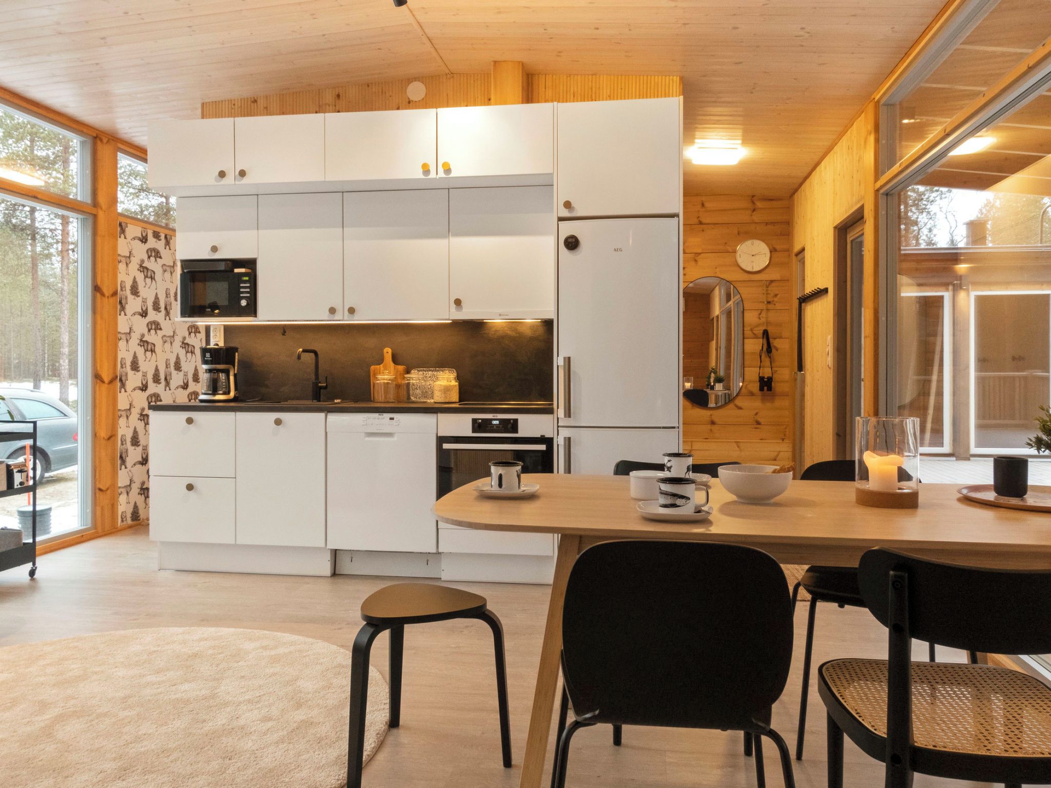 A modern kitchen with white cabinets, a microwave, and a stove. There is a dining table with chairs and a candle on it.