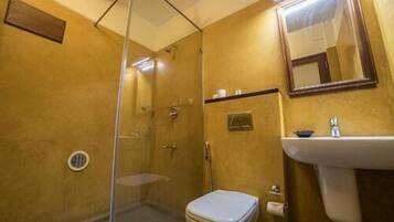 Een badkamer met een douchecabine, een toilet en een wastafel met een spiegel erboven.