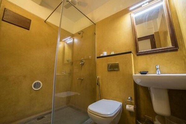 Une salle de bain avec une douche à parois de verre, des toilettes et un lavabo avec un miroir au-dessus.