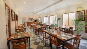 A restaurant with multiple tables and chairs, a checkered floor, and framed artwork on the walls.