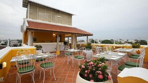 A rooftop terrace with outdoor seating, a covered area, and a view of the cityscape.