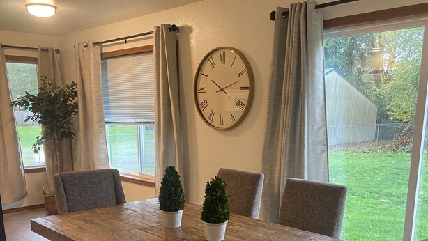 Ein Essbereich mit einem Holztisch, vier Stühlen, einer Uhr und Blick auf den Garten.