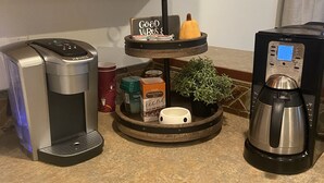 Eine Küchenarbeitsplatte mit Kaffeemaschine, Waage, kleiner Pflanze und einem gerahmten Bild an der Wand.