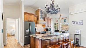 A spacious kitchen with wooden cabinets, a granite countertop, and a central island with bar stools.