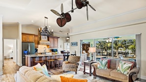 A spacious living area with a large sofa, a coffee table, and a dining area with a kitchen in the background.