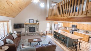 A spacious living area with a fireplace, a high ceiling, and a wooden staircase. - Dogs welcome - Gorgeous, Spacious Cabin in the Pines (Heber)
