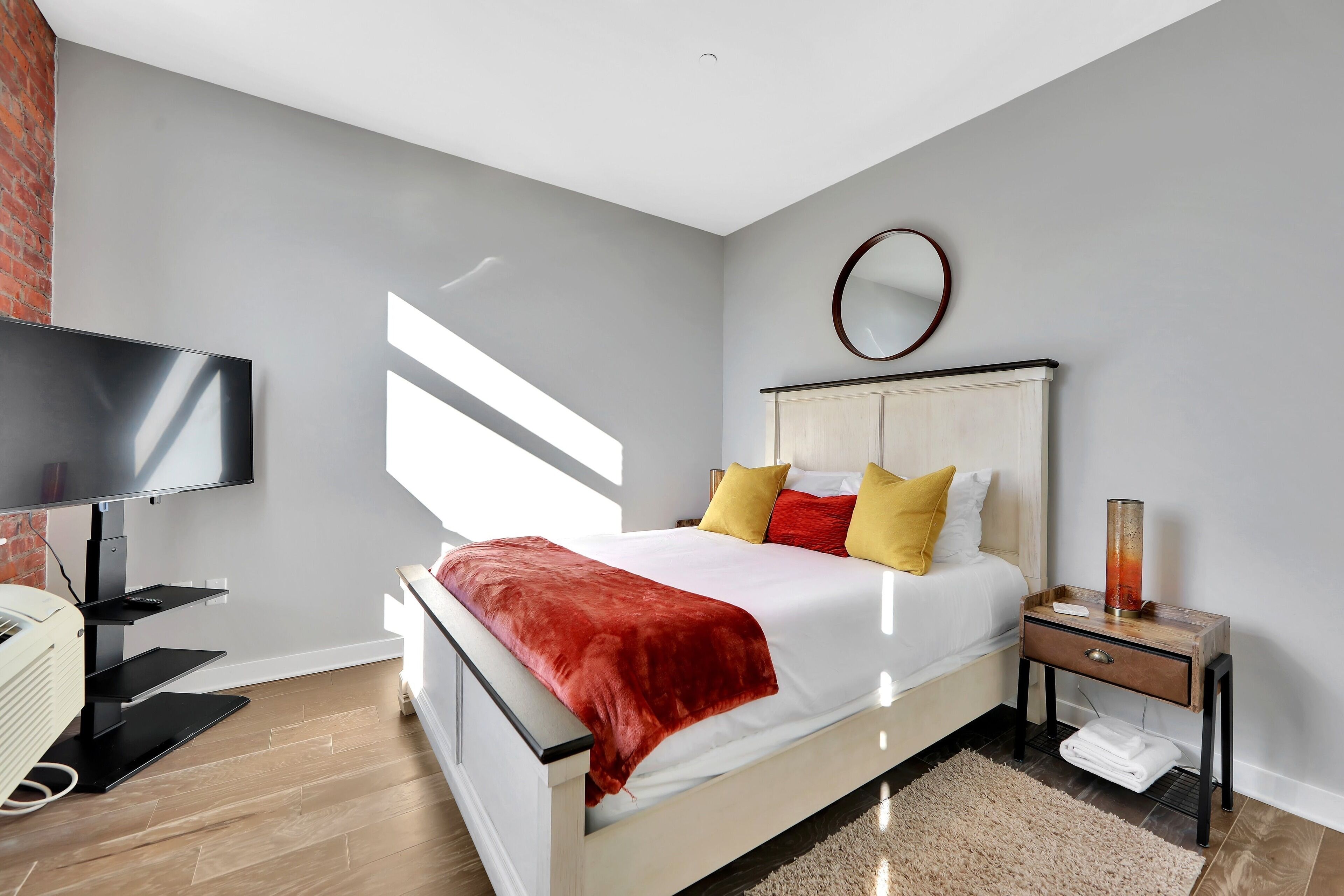 Ein modernes Schlafzimmer mit Bett, Fernseher, Nachttisch und Kamin.