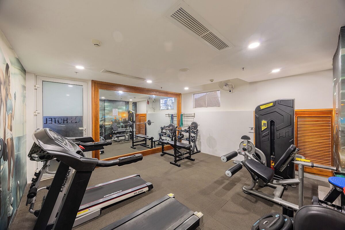 A gym with treadmills, weight machines, and a mirror wall.