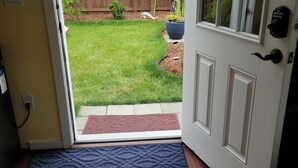 A doorway leading to a backyard with a wooden fence, a potted plant, and a clear sky.