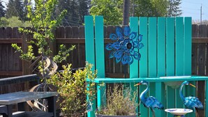 A garden with a wooden fence, potted plants, and decorative bird sculptures.