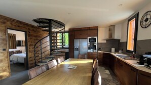 Une cuisine moderne avec une table à manger en bois, un escalier en colimaçon et une vue sur l’extérieur.