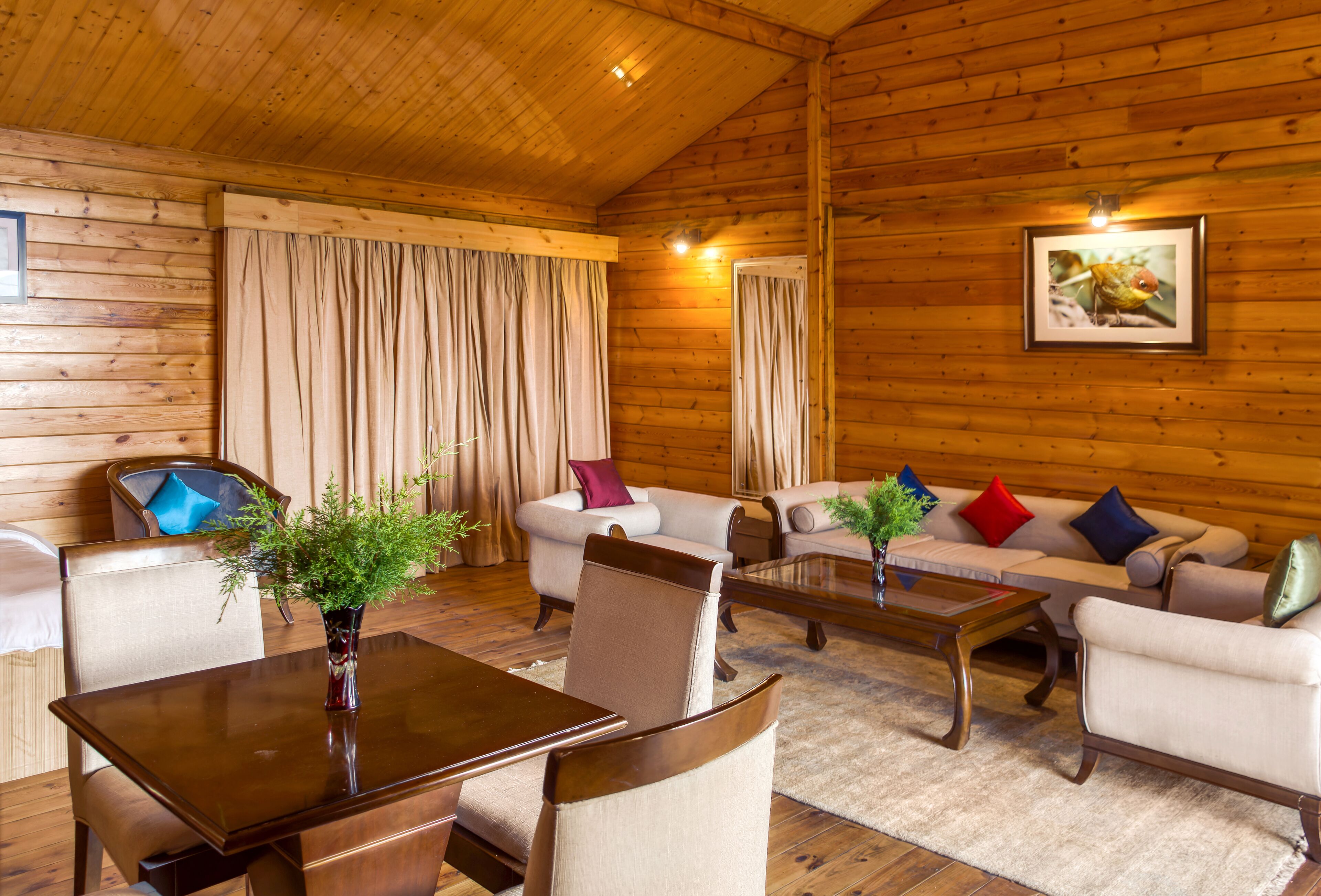 Interior acogedor de una cabaña de troncos, con comedor, sofás y un cuadro en la pared.