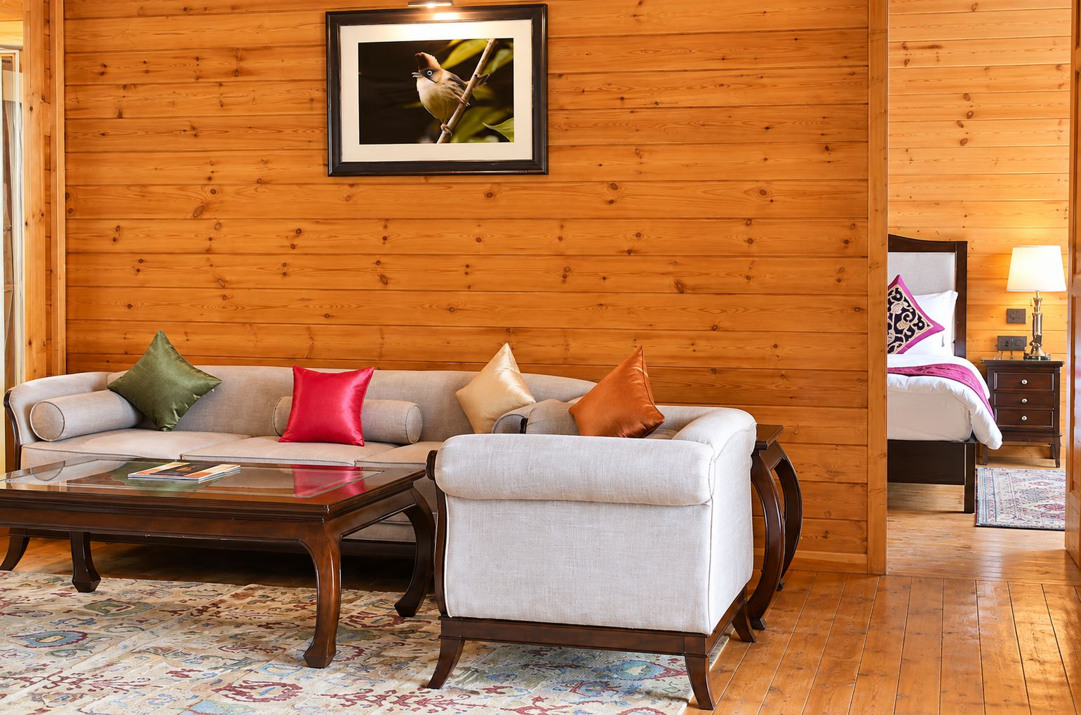 Una habitación con pared de madera, un sofá con cojines, una mesita de centro y un cuadro enmarcado en la pared.