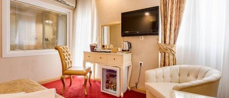 A hotel room with a bed, a desk with a computer, a television, and a chair.