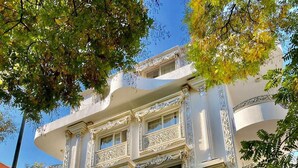 Un edificio de varios pisos con detalles arquitectónicos ornamentales, un letrero destacado que dice 'Hotel Twins Boutique' y varias banderas.