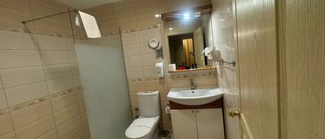 A bathroom with a toilet, sink, and shower.